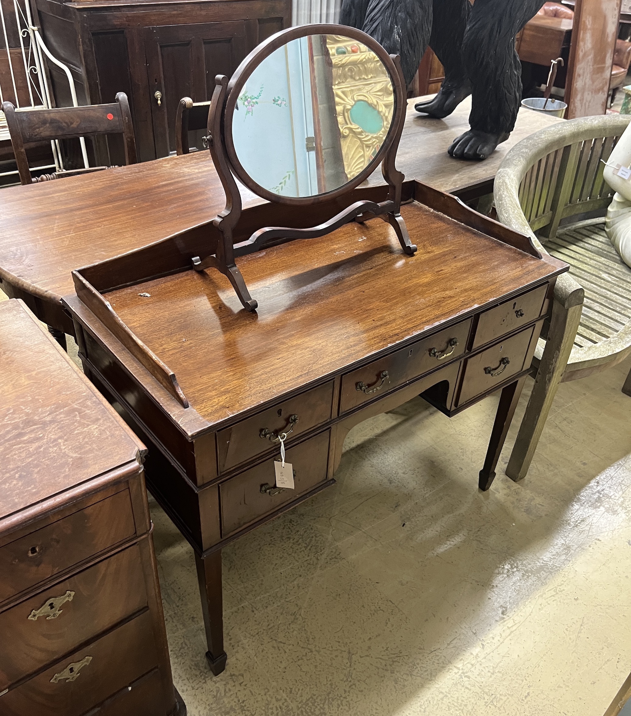 An early 20th century George III style mahogany kneehole dressing table, width 104cm, depth 52cm, height 88cm and a skeleton framed toilet mirror